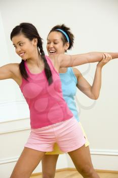Royalty Free Photo of a Woman Helping Another Woman With Positioning on Her Yoga Pose