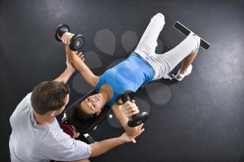 Royalty Free Photo of a Man assisting woman lifting weights at gym