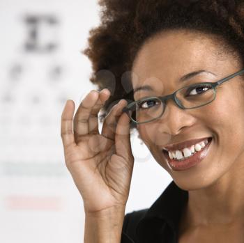 Royalty Free Photo of a Woman Wearing Eyeglasses With a Medical Eye Chart in the Background