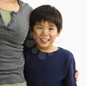 Royalty Free Photo of a Boy Standing Smiling With Mother Standing Next to Him With Her Arm Around Him