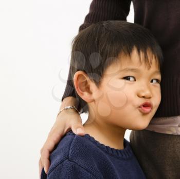 Royalty Free Photo of a Young Boy Making a Funny Face Standing Next to His Mother