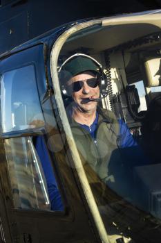 Portrait of helicopter pilot sitting in cockpit looking at viewer.