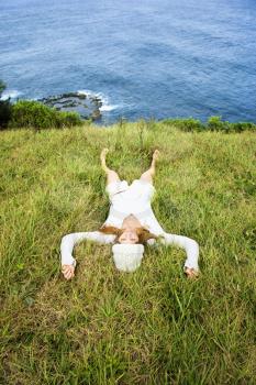 Royalty Free Photo of a Young Woman Relaxing in the Grass Near the Ocean in Maui, Hawaii