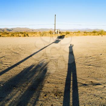 Royalty Free Photo of a Landscape With a Long Shadow of a Man and Desert in the Background