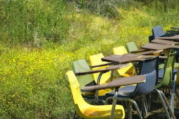 Royalty Free Photo of a Bunch of Old School Chairs in a Grassy Field