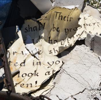 Pages of old weathered bible verse lying in junkyard.