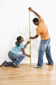 African American male and female measuring wall.