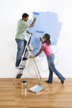 Royalty Free Photo of a Smiling Couple Painting a Wall Blue