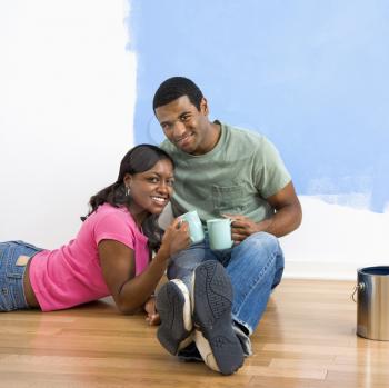 Royalty Free Photo of a Couple Relaxing Together With Coffee Next to a Half-Painted Wall