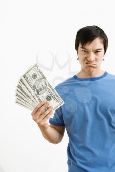 Royalty Free Photo of a Young Man Holding Money With Disgust on His Face