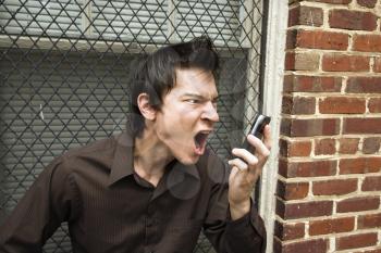 Royalty Free Photo of an Angry Man Yelling Into a Cellphone 