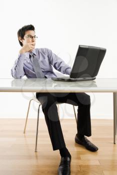 Royalty Free Photo of a Businessman Sitting at a Desk Working on a Laptop Computer