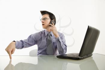Royalty Free Photo of a Businessman Sitting at a Desk on a Cellphone With an Angry Expression