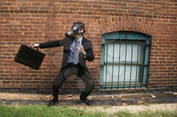 Royalty Free Photo of a Businessman Standing Next to a Brick Wall Wearing a Gas Mask in a Fighting Stance