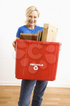 Royalty Free Photo of a Woman Smiling While Holding a Recycling Bin