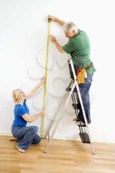 Royalty Free Photo of a Middle-Aged Couple Measuring a Wall With Tape