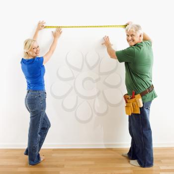 Royalty Free Photo of a Couple Measuring a Wall With Tape