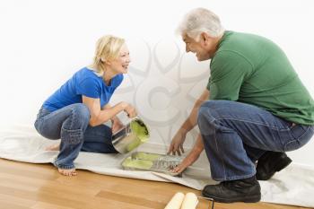 Royalty Free Photo of a Middle-aged Couple Pouring Paint into a Tray on a Drop Cloth
