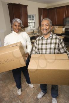 Portrait of smiling senior african american man and woman with moving boxes in a new home.   Vertical shot.