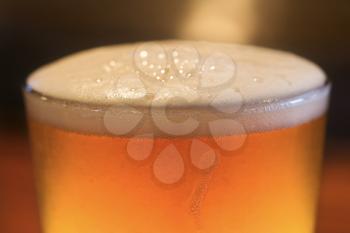 Close-up of glass of beer with foam on top. Vertical shot.