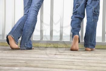 Rear view of brother and sister's legs as they stand on on the boardwalk. Horizontal shot.