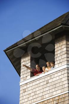 Low angle view of a family looking and pointing out a tower window. Vertical shot.