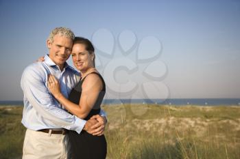 Attractive causcasian couple embrace and smile at the camera. Horizontal shot.
