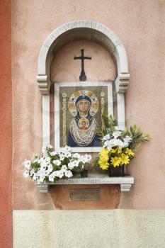 Madonna and Child mosaic at outdoor shrine. Flowers have been left at the shrine. Vertical shot.