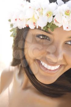 Attractive young Hawaiian woman with a lei on her head smiling. Vertical shot.
