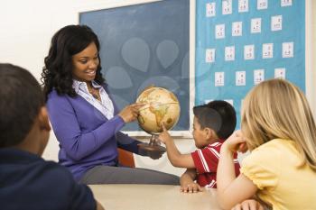 Teacher giving geography lesson in school classroom with globe.