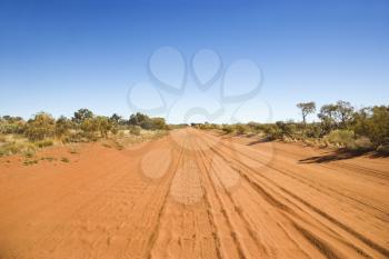Desert road in the remote Australian Outback. Tread marks can be seen imprinted in the dirt. Horizontal shot.