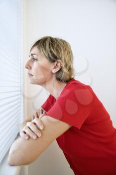 Caucasian adult woman looking out of window.