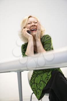 Caucasian middle aged businesswoman in office on cellphone laughing.