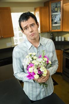 Man holding bouquet of flowers looking sorry and asking forgiveness.