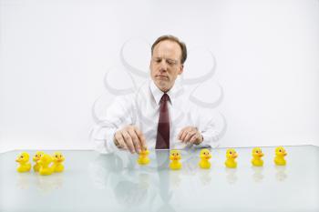 Portrait of middle aged  Caucasian businessman sitting at desk putting ducks in a row.