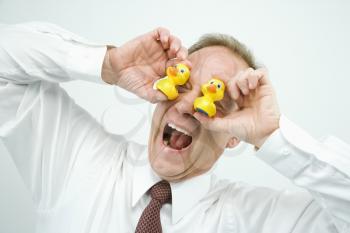 Portrait of middle aged  Caucasian businessman playing with rubber ducks making funny face.