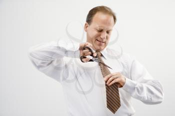 Caucasian middle aged businessman cutting off necktie with scissors.