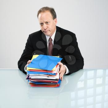 Caucasian middle aged businessman with stack of folders.
