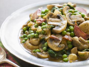 Royalty Free Photo of Mushroom and Pea Curry with Roasted Garlic on a Pewter Plate