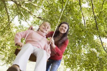 Royalty Free Photo of a Woman Pushing a Girl on a Swing