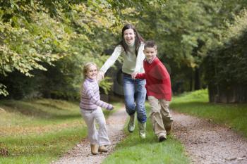 Royalty Free Photo of a Mother and Two Children Running on a Path