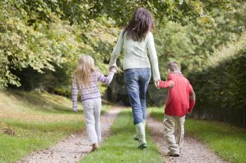 Royalty Free Photo of a Mother and Children Walking on a Path From the Back