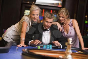 Royalty Free Photo of a Man and Two Women at a Roulette Table