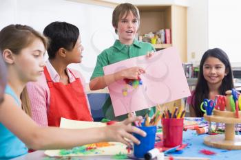 Royalty Free Photo of a Student Showing His Teacher and Classmates His Artwork