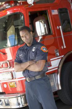 Royalty Free Photo of a Firefighter Standing Beside the Truck