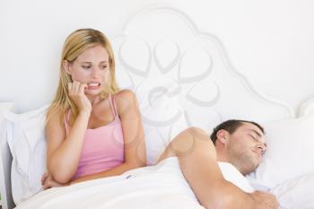 Royalty Free Photo of a Young Couple in Bed With the Woman Looking Worried