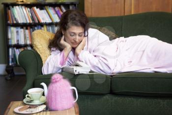 Royalty Free Photo of a Woman Lying on a Sofa Watching a Telephone