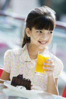 Royalty Free Photo of a Girl Having Juice and Cake