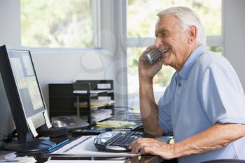 Royalty Free Photo of a Man at a Computer Talking on a Telephone