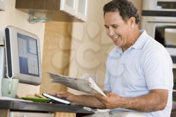 Royalty Free Photo of a Man at the Computer With a Newspaper